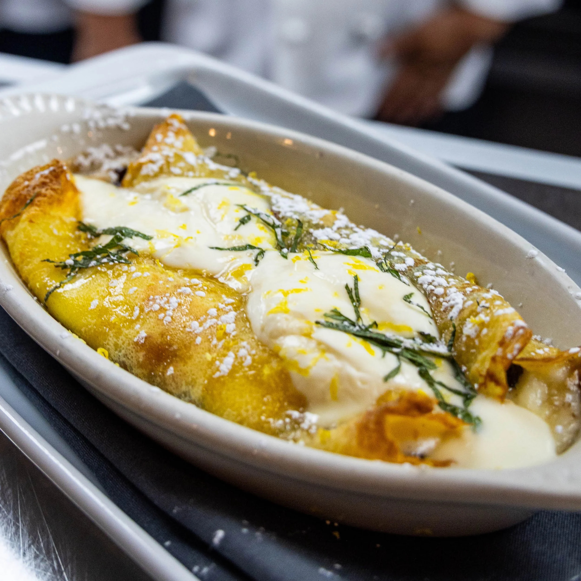 Warm dessert crepes with lemon cream, powdered sugar and fresh mint