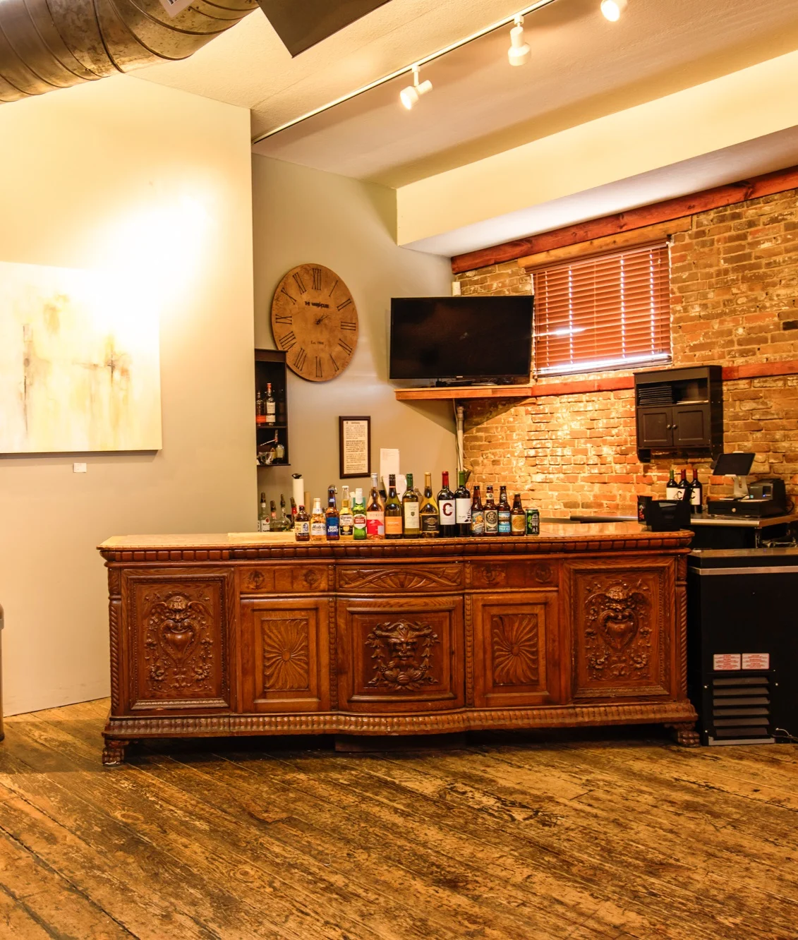 Carved antique wood bar with wine and spirits against exposed brick