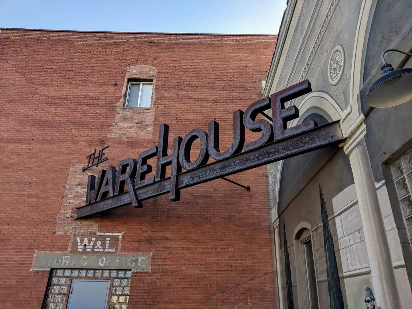 The Warehouse steel blade sign mounted on the historic red brick building