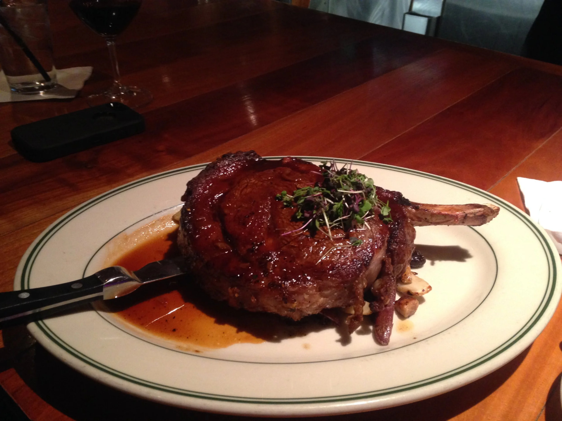 Bone-in ribeye with pan jus and micro greens at the bar