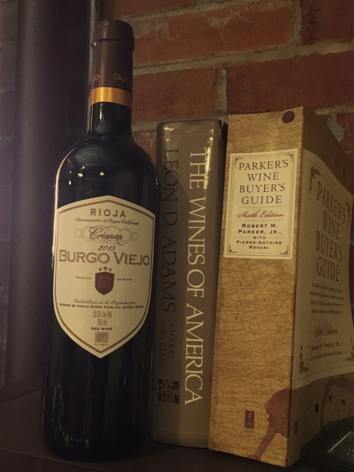 Rioja bottle beside wine reference books on a brick ledge