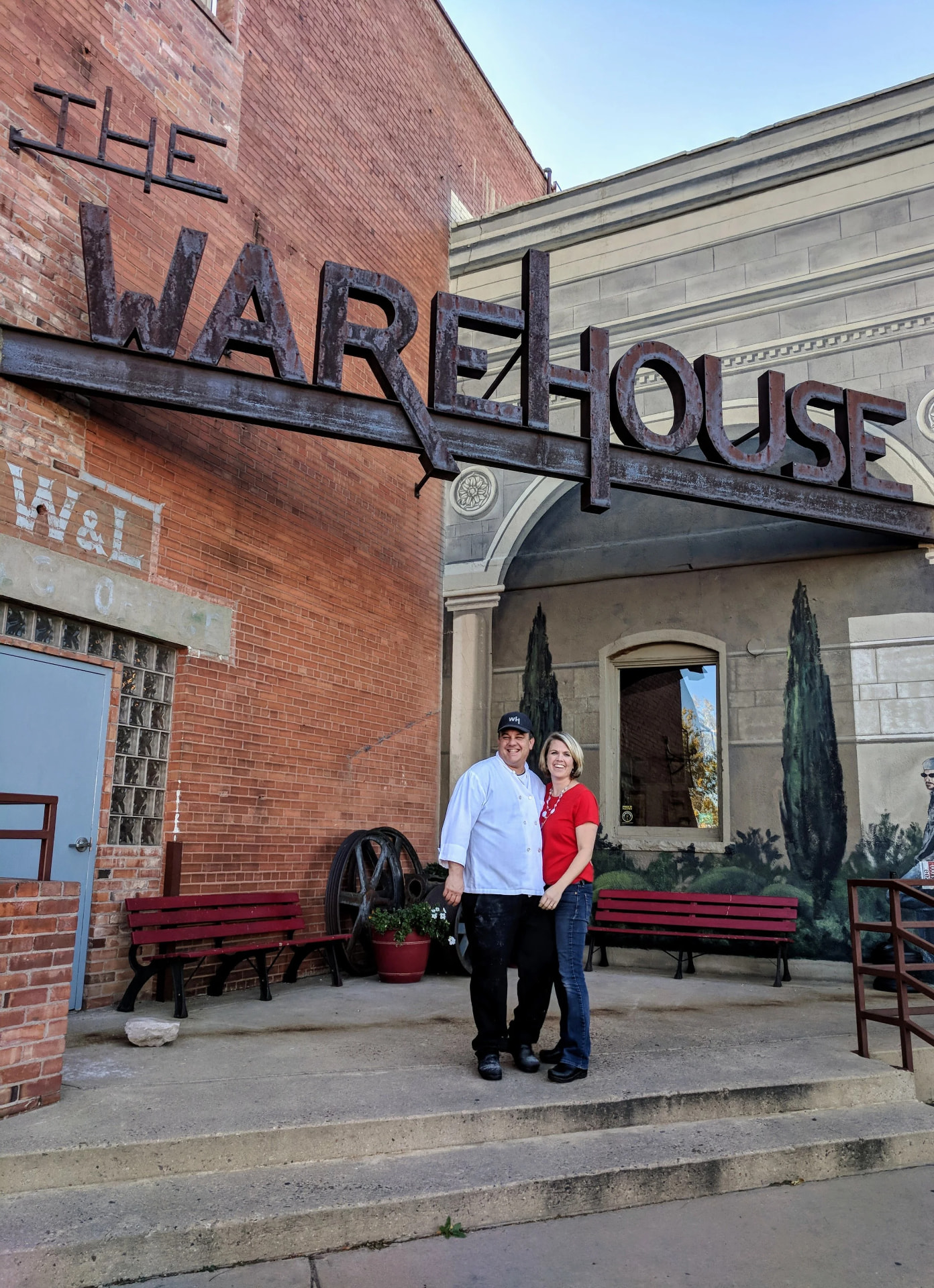 The Warehouse owners standing beneath the restaurant's steel sign